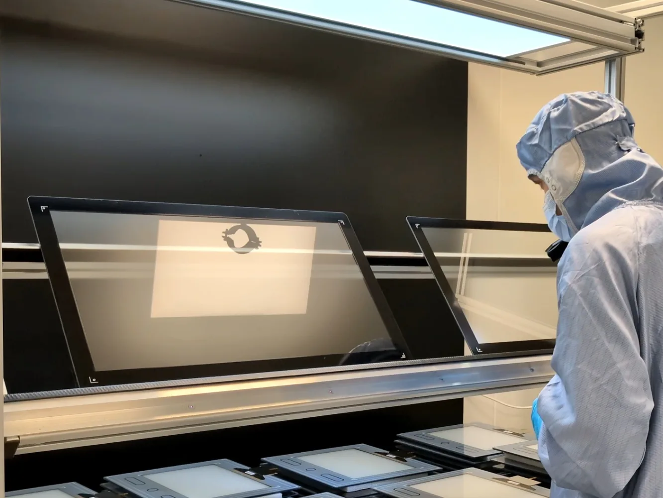 Technician inspecting bonded cover-glass panels on a light table